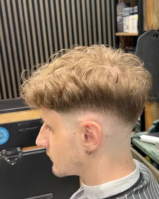 Dégradé sur cheveux blonds bouclés, volume sur le dessus, vu de profil