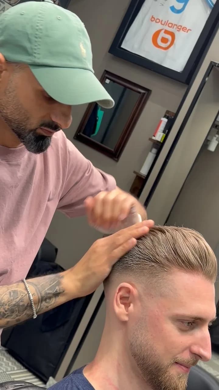 Le barbier coiffe à la main les cheveux d’un client après une coupe dégradée