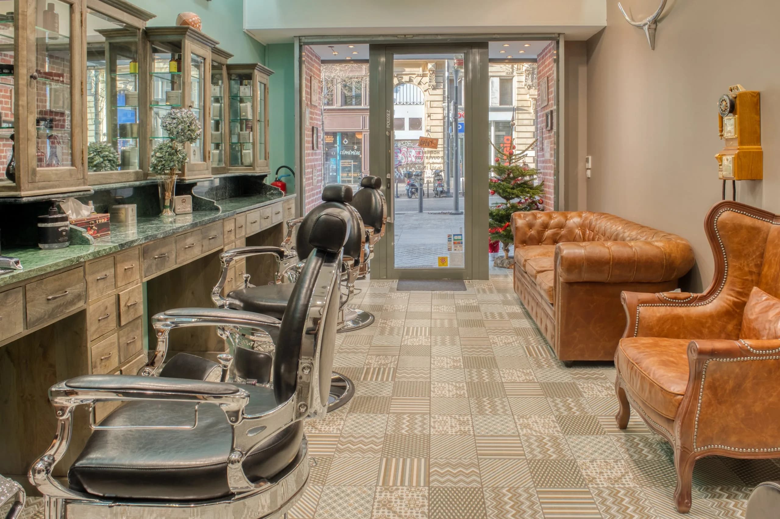 Les postes de coupe du salon, fauteuils de barbier alignés face aux miroirs, canapés en cuir côté vitrine